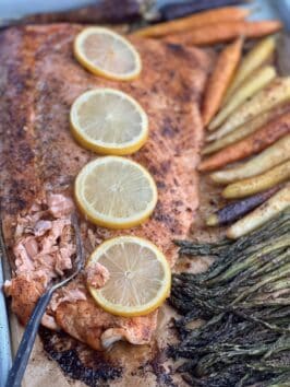 sheet pan salmon topped with lemon sliced with vegetables