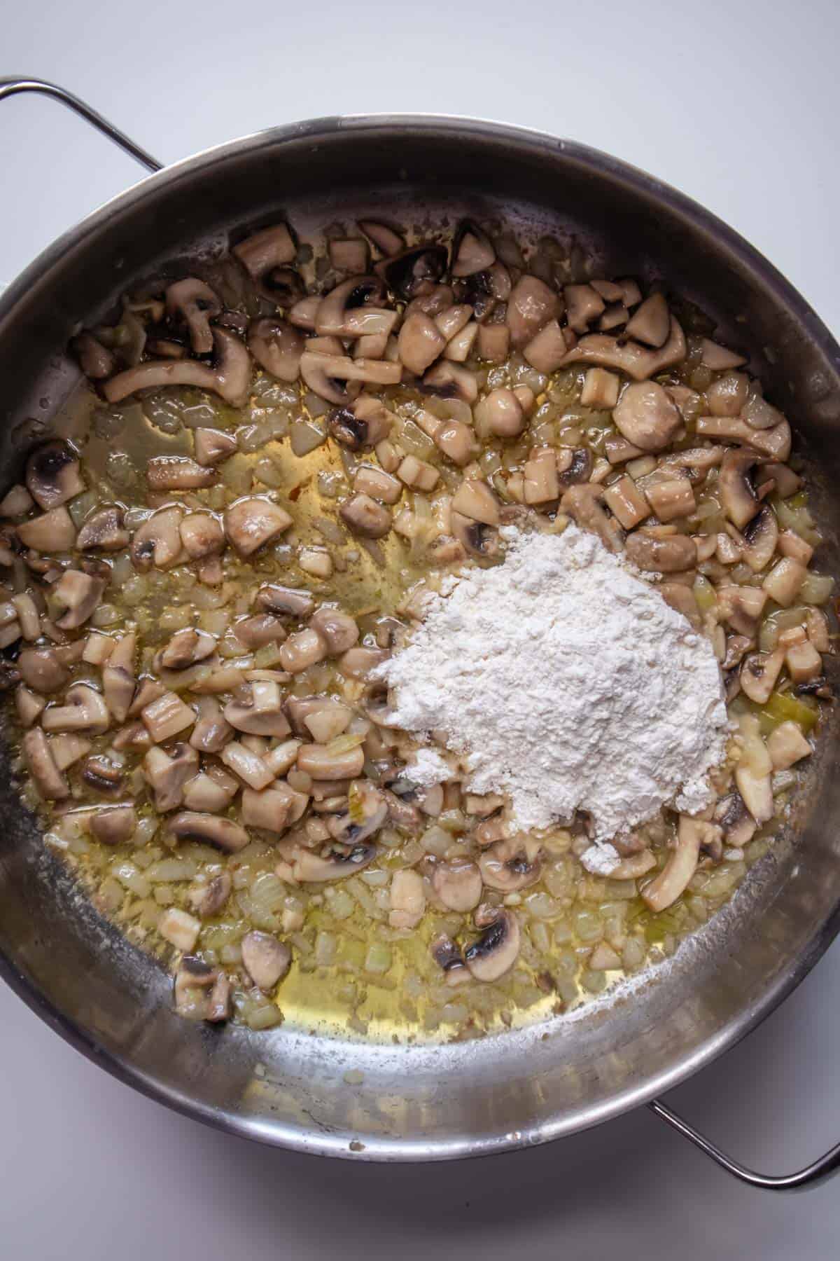 onions, mushrooms, and butter in a pot with flour on top 