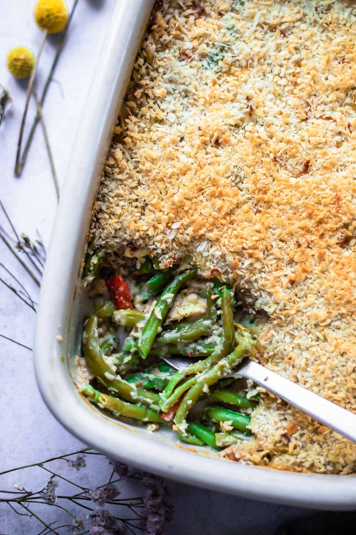 cheesy green beans topped with panko breadcrumbs in a white baking dish