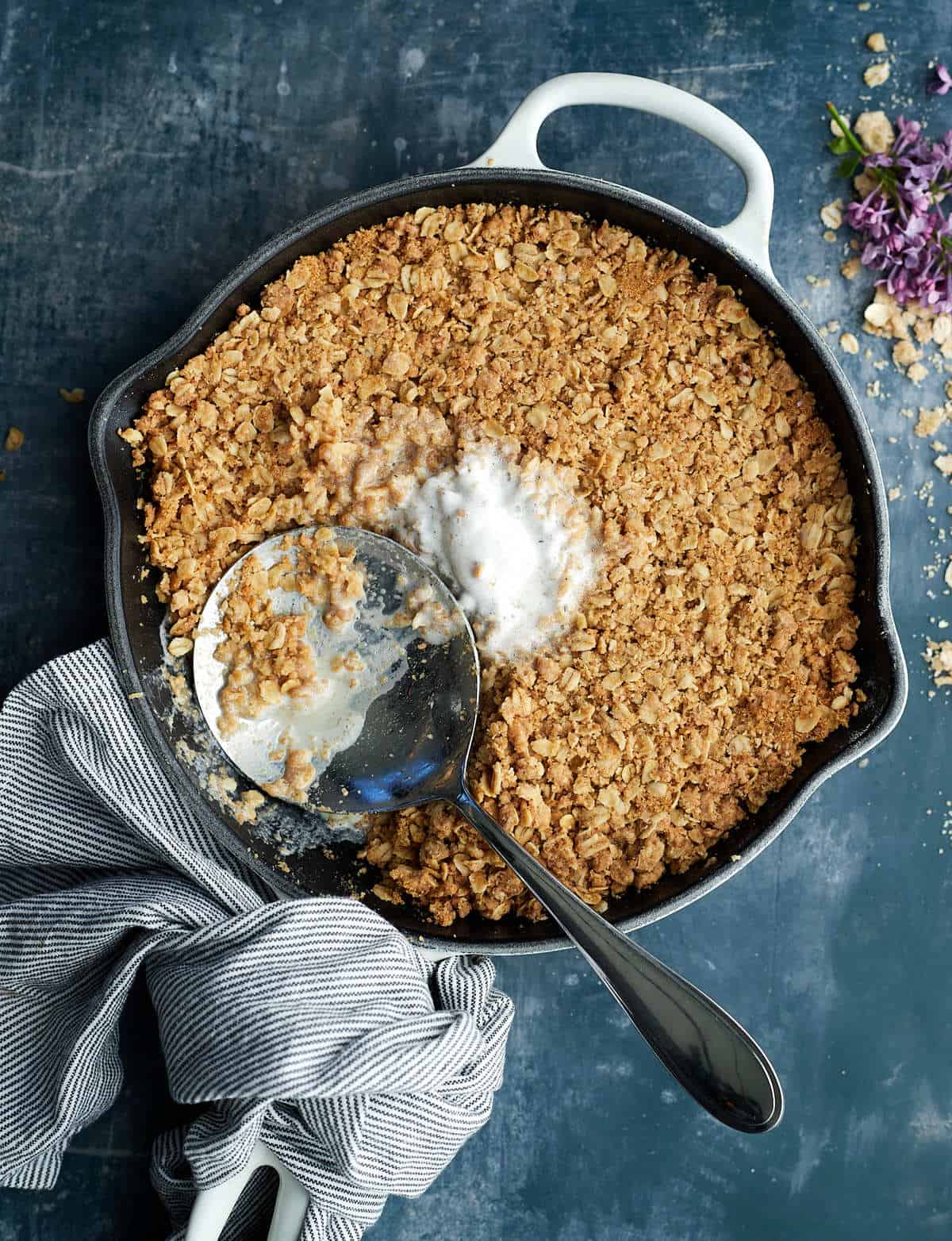 overhead baked oat crumble in a skillet with ice cream and serving spoon