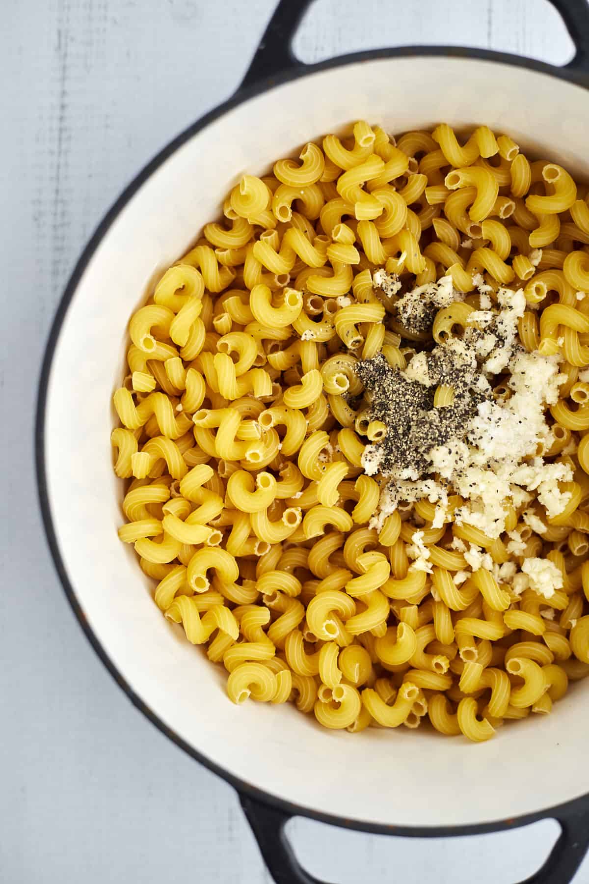 raw cavatappi noodles topped with garlic, salt, and pepper