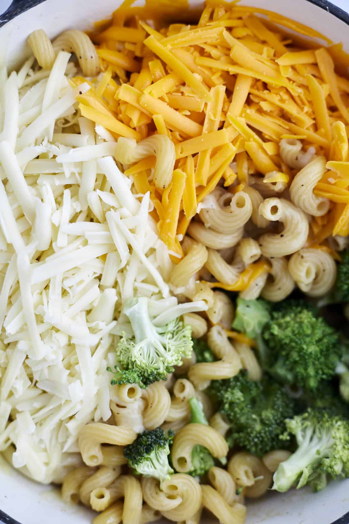 close up image of cavatappi noodles, broccoli, Mozzarella, and Cheddar cheese in a pot 