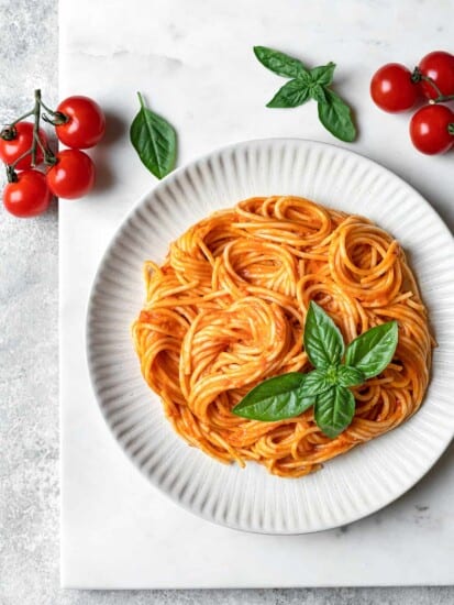 plate of spicy spaghetti arrabbiata garnished with fresh basil and cherry tomatoes