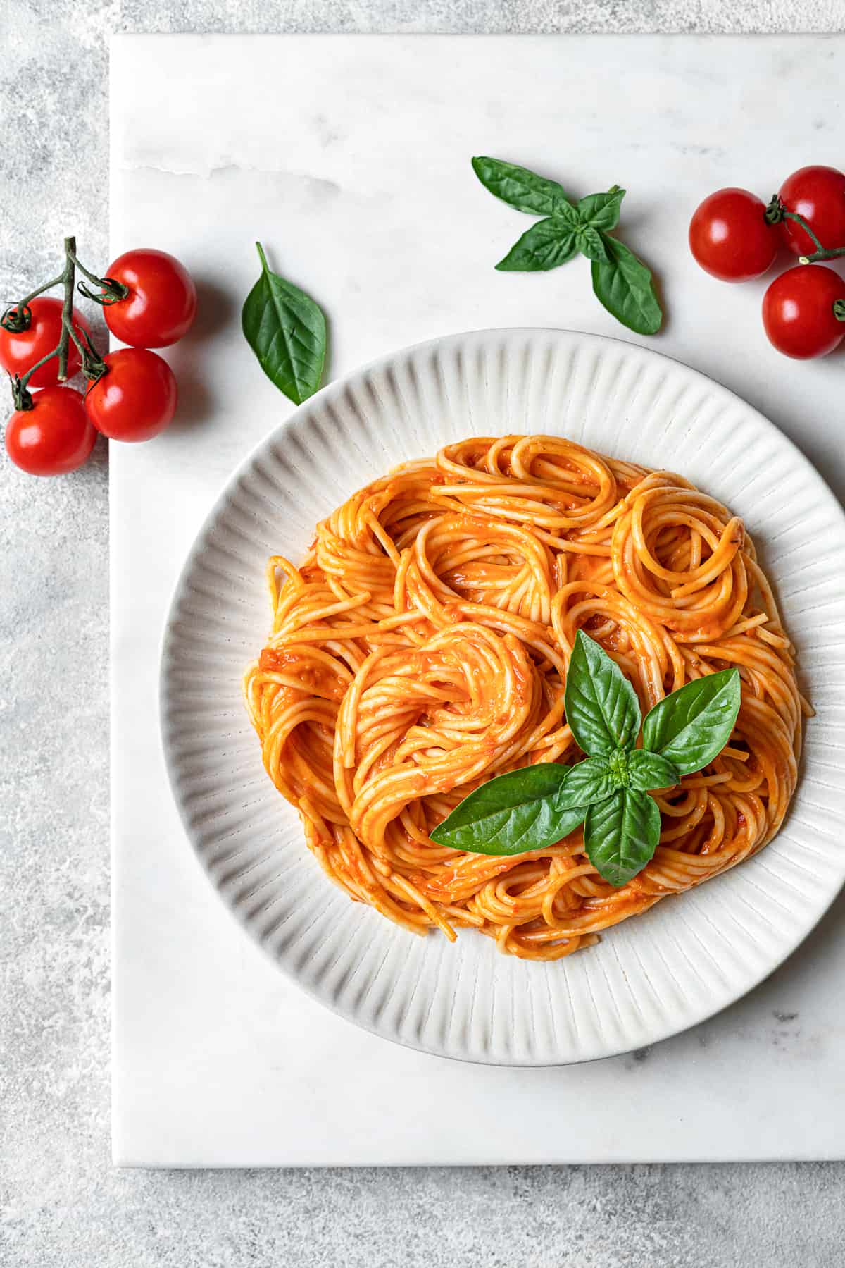 plate of spicy spaghetti arrabbiata garnished with fresh basil and cherry tomatoes