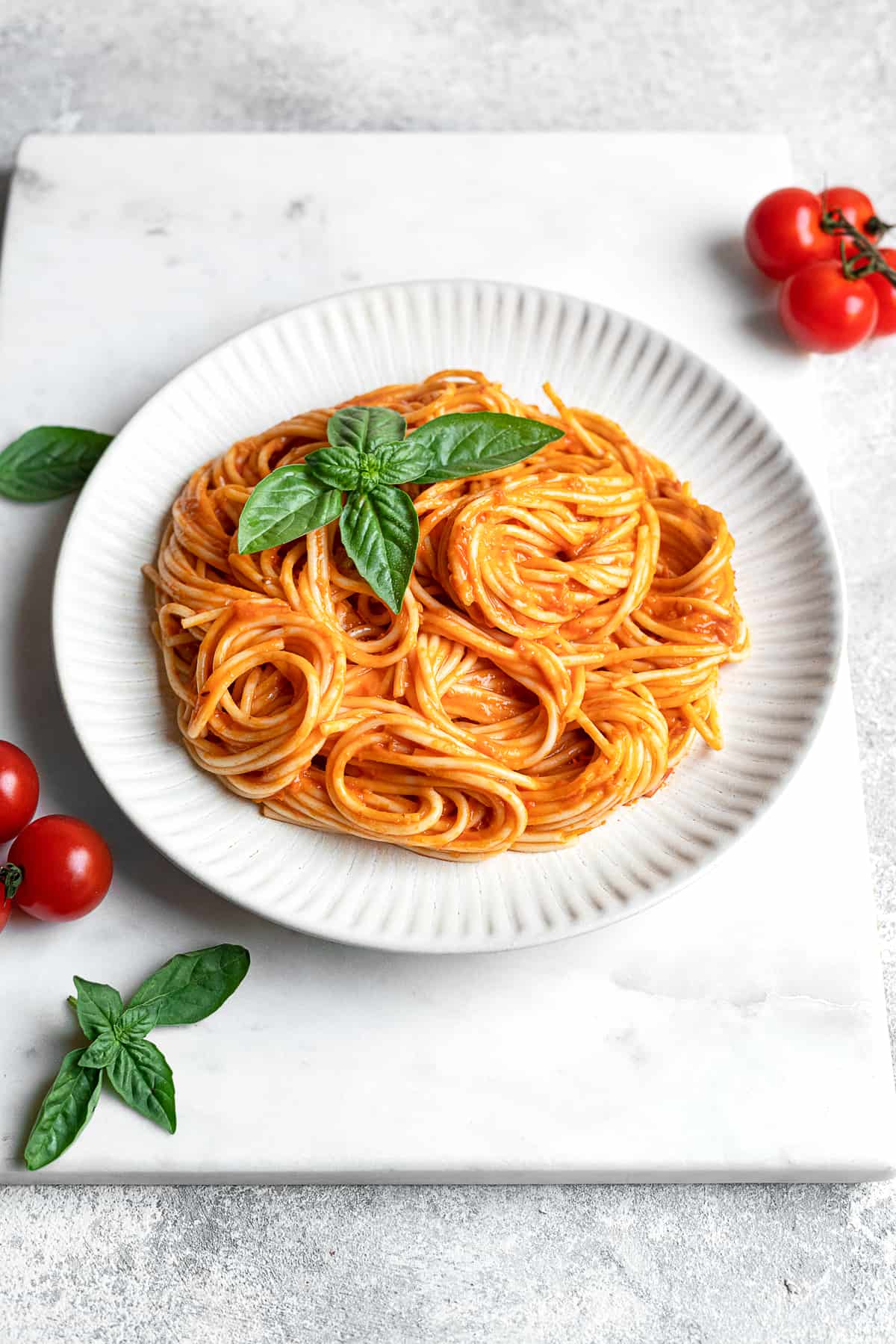 plate of spicy spaghetti arrabbiata garnished with fresh basil and cherry tomatoes
