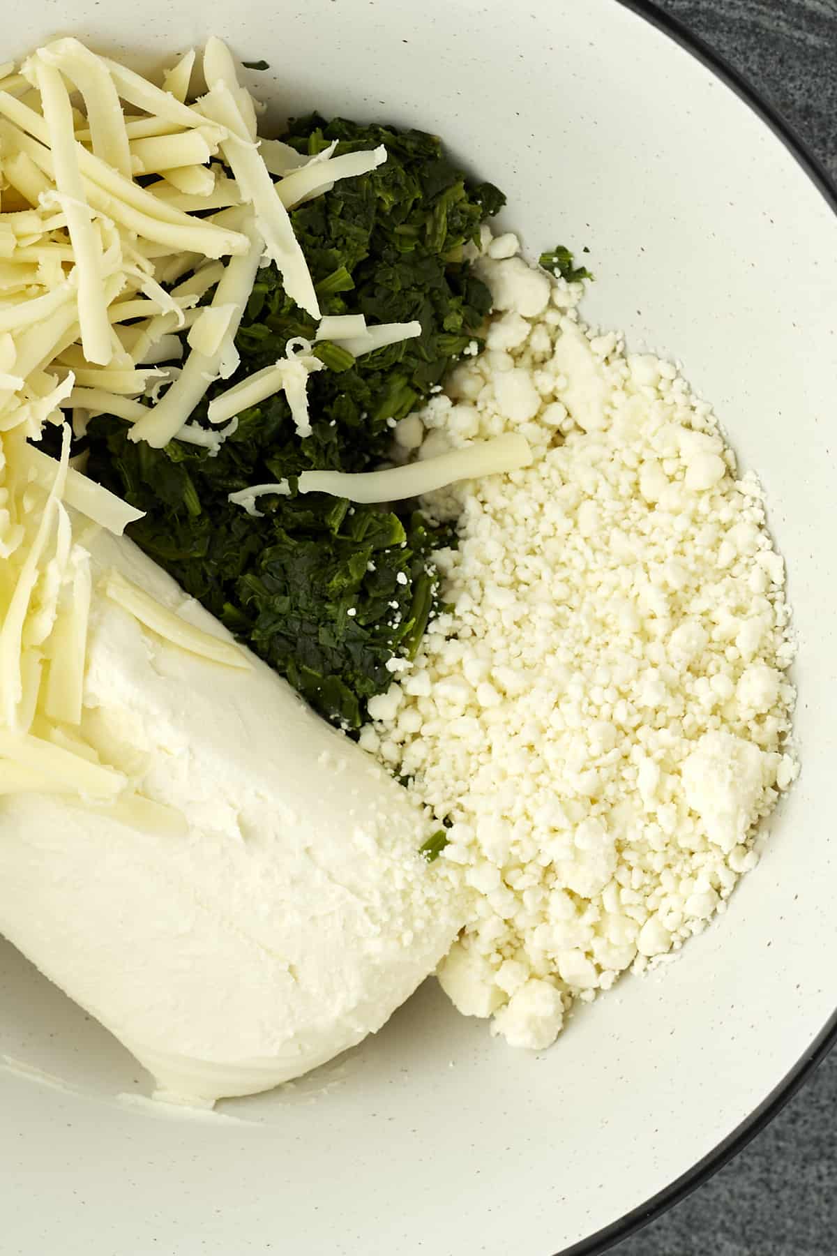 cream cheese, spinach, mozzarella, and parmesan in a white bowl