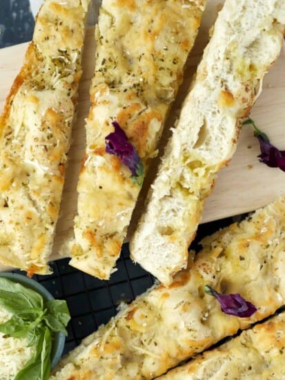 no knead focaccia bread sliced diagonally on a cutting board.