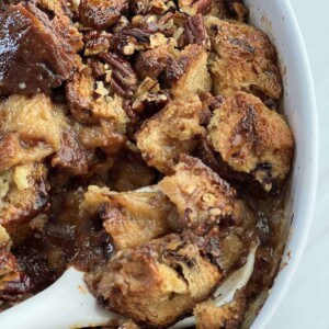 close up image of a spoon scooping a serving of panettone bread pudding from a baking dish