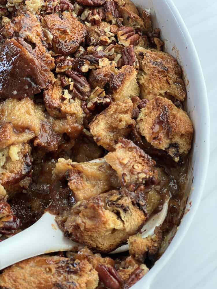 close up image of a spoon scooping a serving of panettone bread pudding from a baking dish