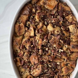overhead image of panettone bread pudding with pecan pie filling in an oval baking dish.