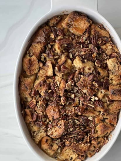 overhead image of panettone bread pudding with pecan pie filling in an oval baking dish.