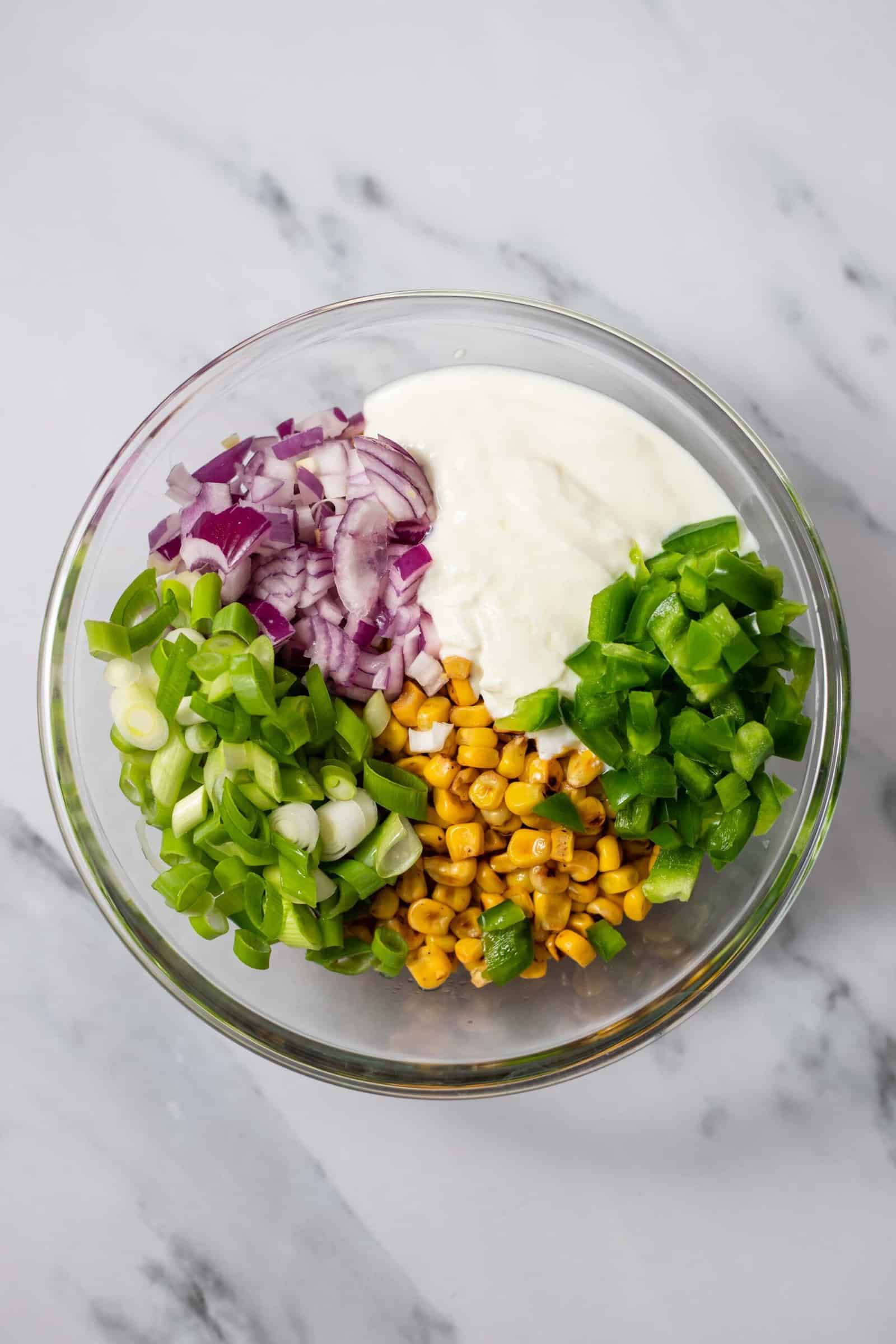 red onion, mayo, green onions, roasted corn, and bell peppers in a bowl for elote corn salad