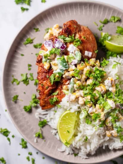 a plate of chipotle chicken with elote corn salad over a bed of rice