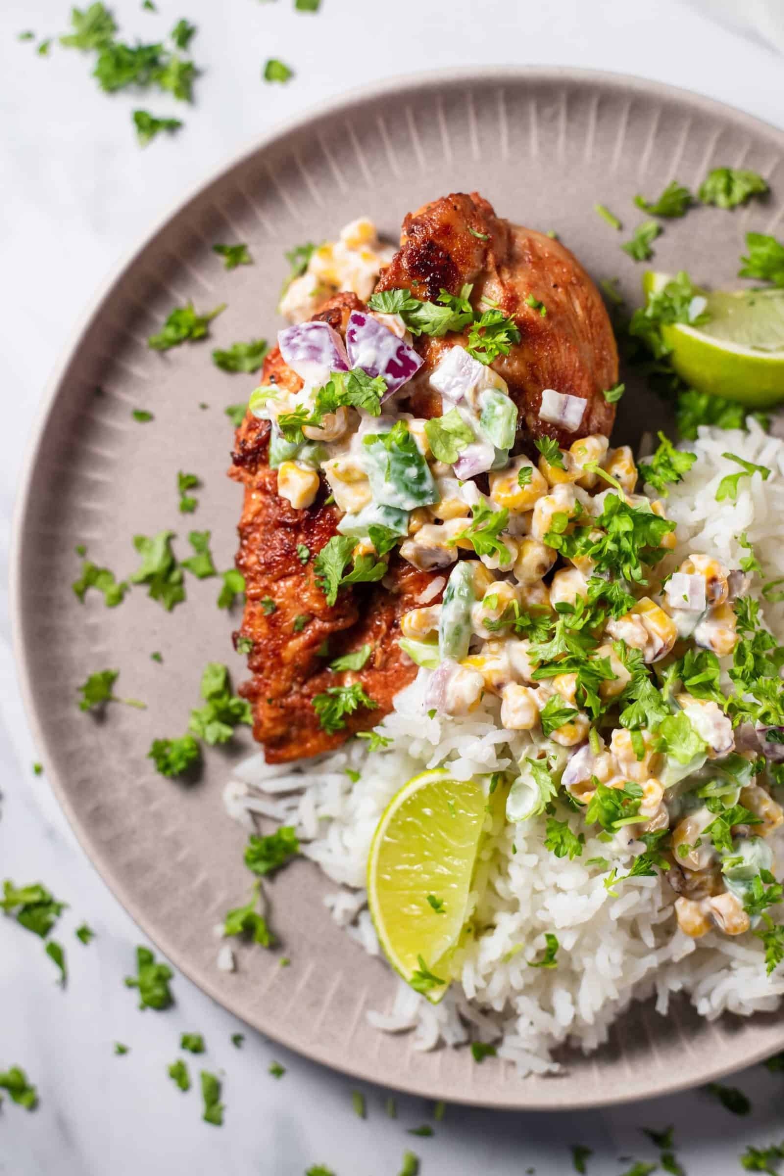 chipotle chicken with elote corn salad on top of rice