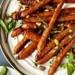 Oven roasted carrots with tahini dressing topped with mint and pistachios.