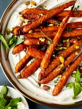 Oven roasted carrots with tahini dressing topped with mint and pistachios.