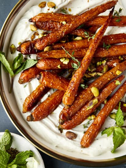 Oven roasted carrots with tahini dressing topped with mint and pistachios.