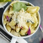 a mug full of one pot creamy tuscan chicken pasta topped with grated Parmesan