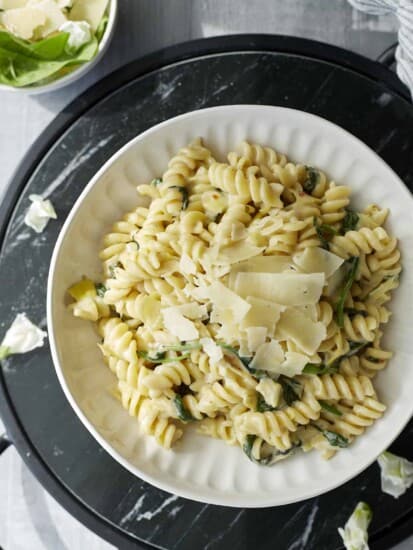 a plate of one pot spinach and artichoke pasta topped with Parmesan flakes