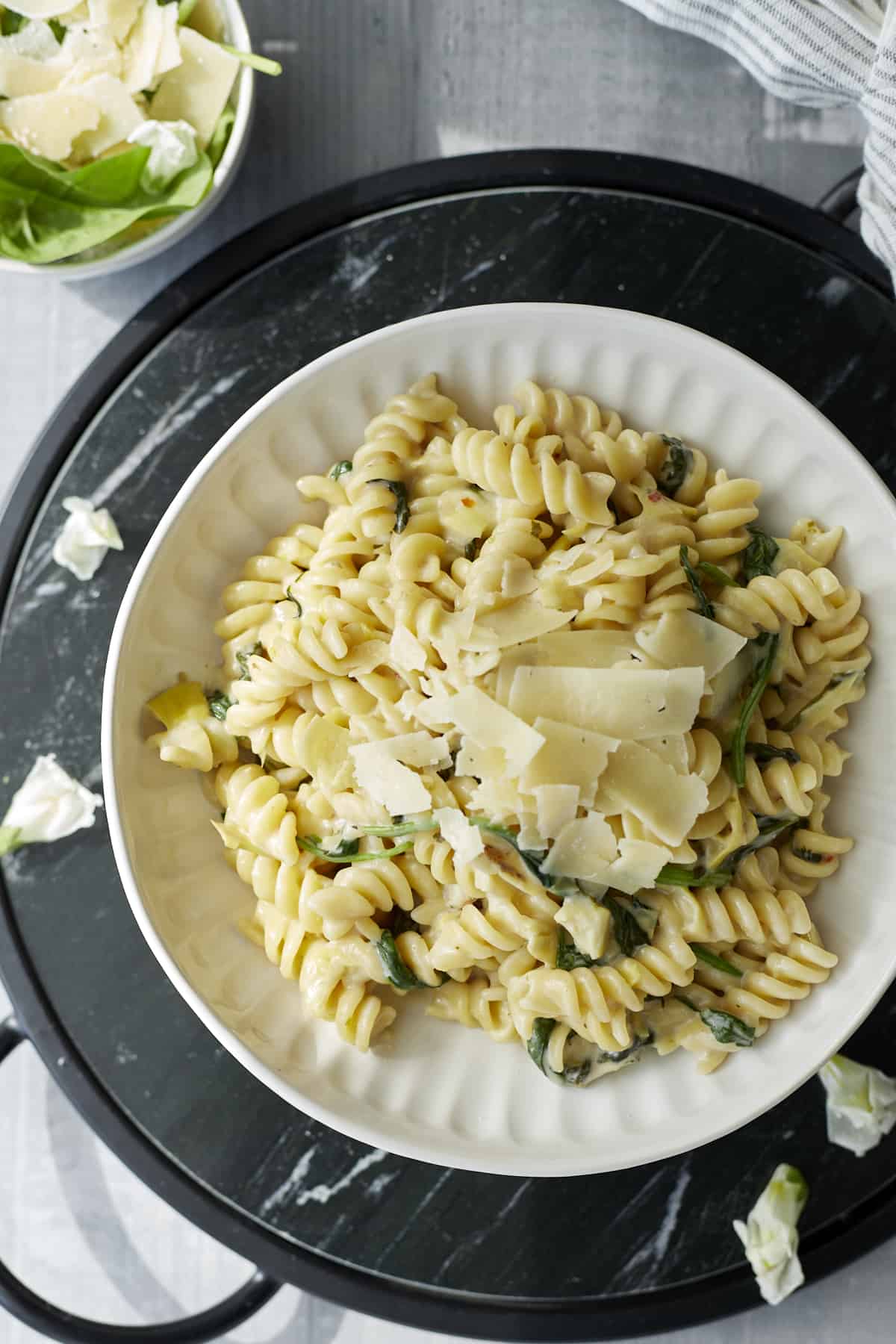 a plate of one pot spinach and artichoke pasta topped with Parmesan shavings