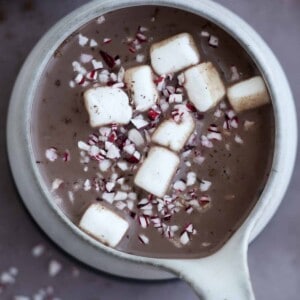 overhead image of a mug of hot chocolate topped with marshmallows and candy cane pieces