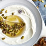 A bowl of whipped ricotta dip topped with roasted pistachios and honey.