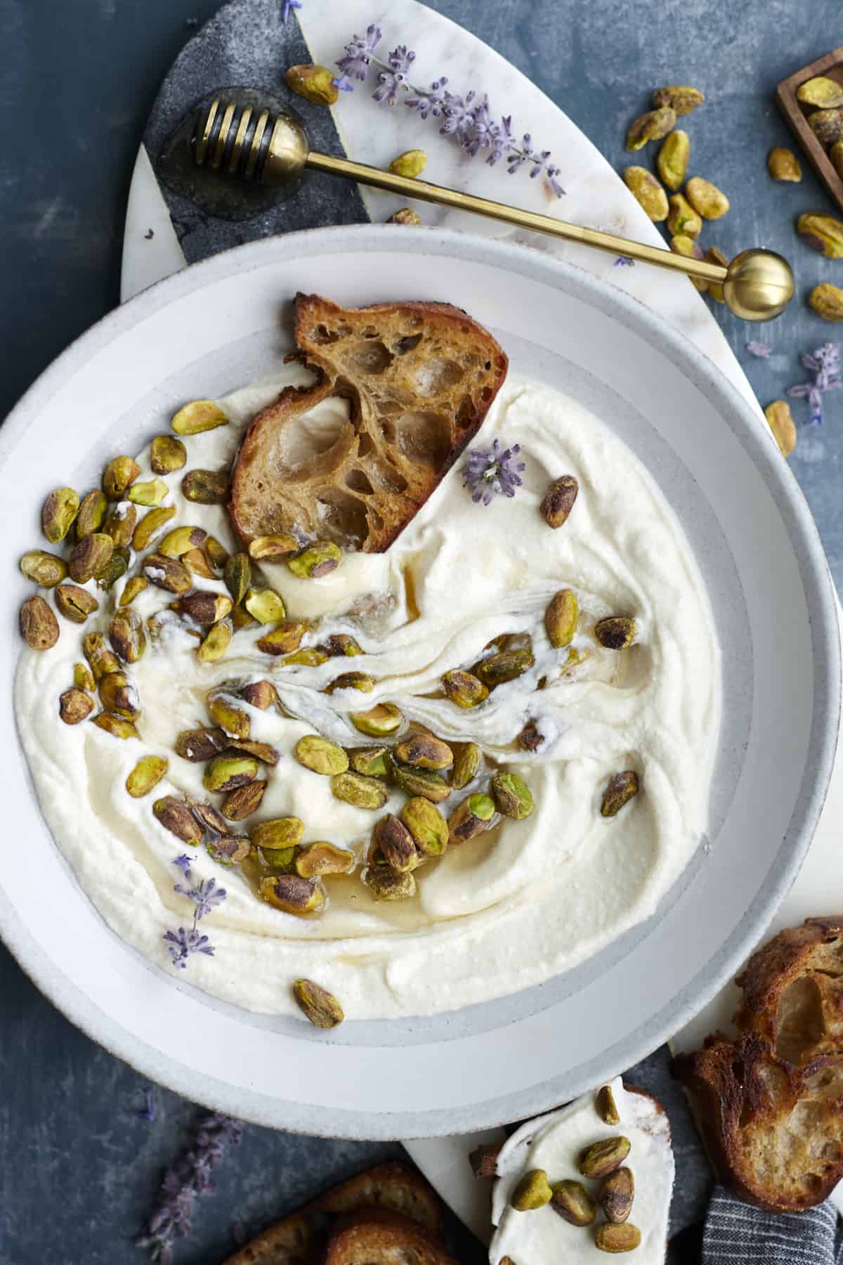 gray bowl with whipped ricotta mixed with pistachios, honey and crusty baguette toast
