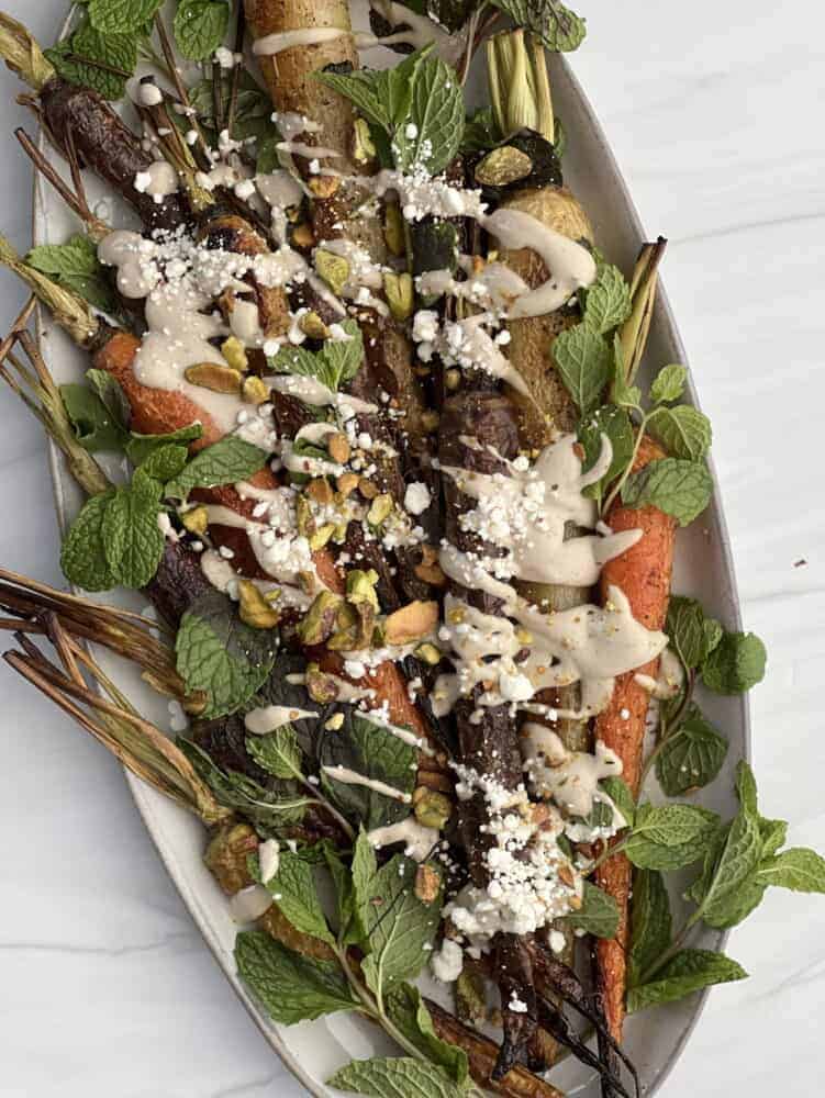 a plate of oven roasted whole carrots topped with tahini dressing