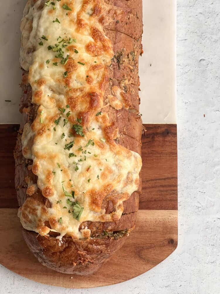 Overhead image of cheesy garlic bread sliced into pull apart bread on a cutting board