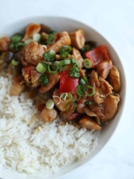 a bowl of white rice topped with kung pao chicken