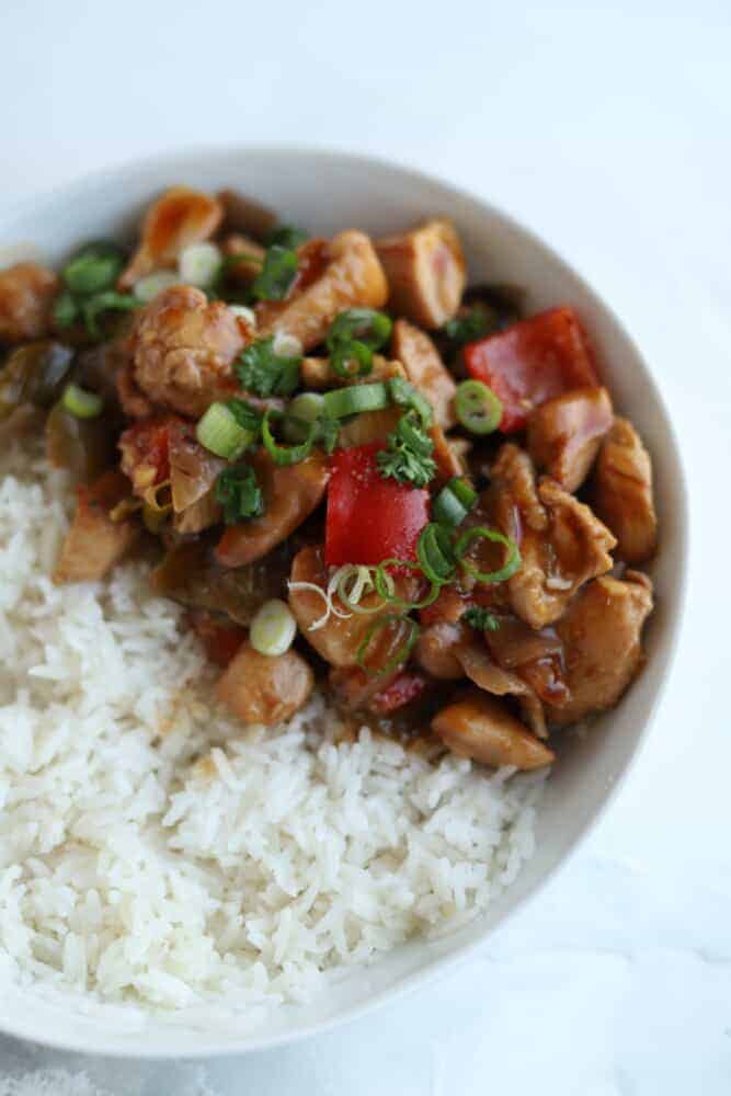 a bowl of white rice topped with kung pao chicken