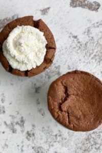 overhead image of two chocolate souffles in ramekins with one topped with whipped cream