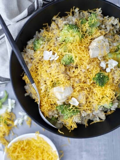 a skillet of broccoli and cheese chicken with a serving spoon on the side