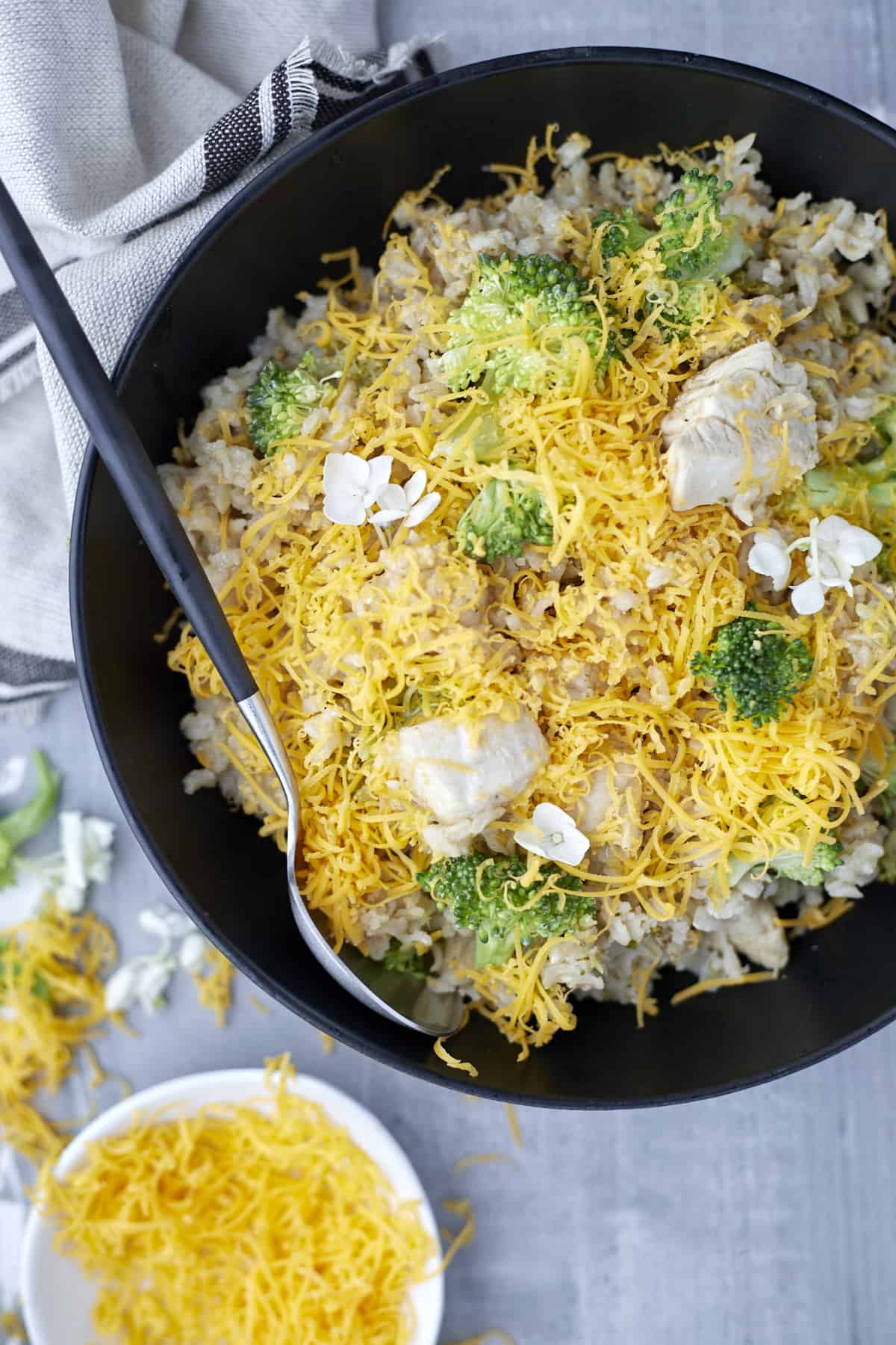 a skillet of broccoli and cheese chicken with a serving spoon on the side