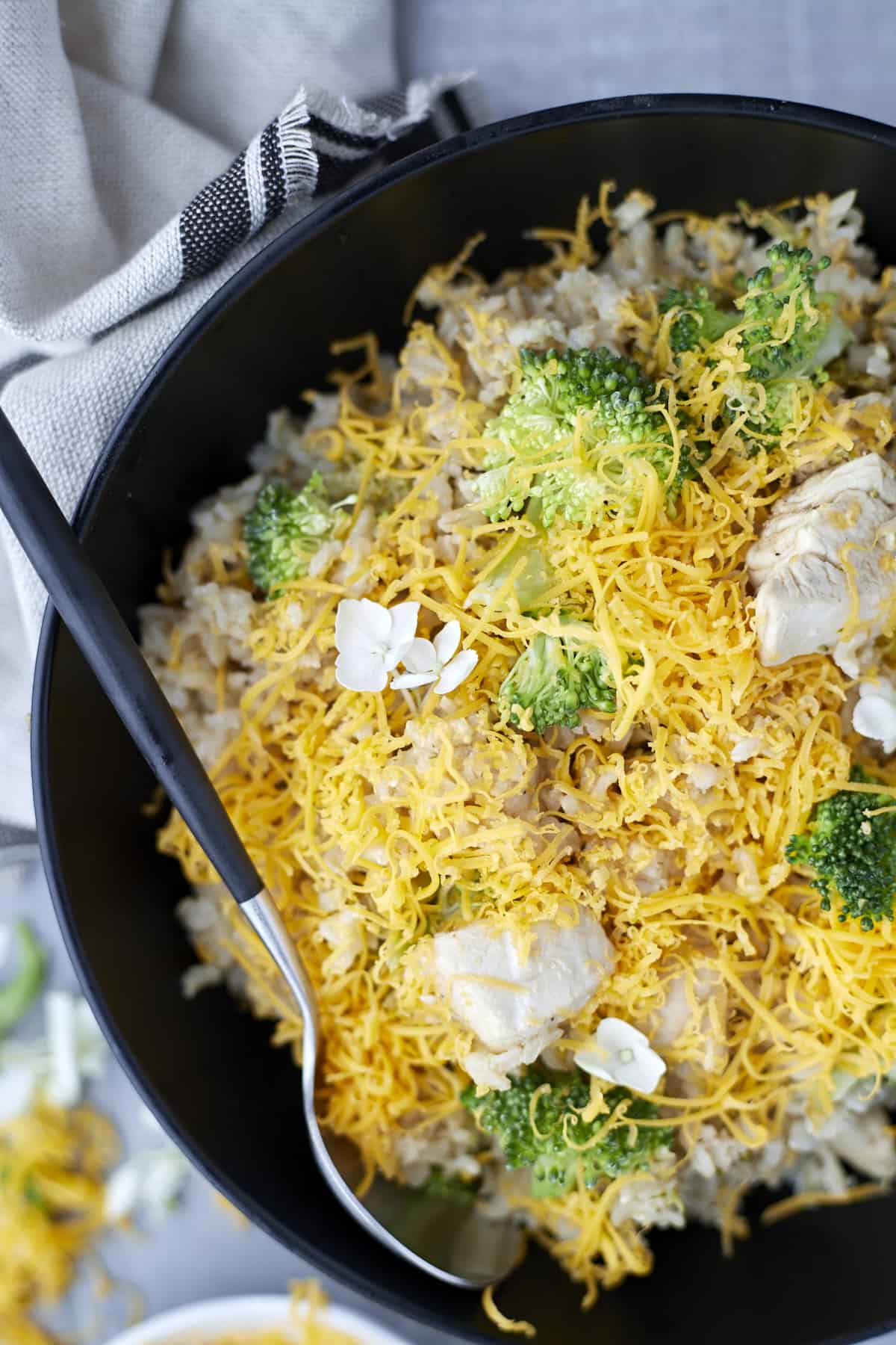 close up image of chicken and broccoli in a skillet topped with cheese