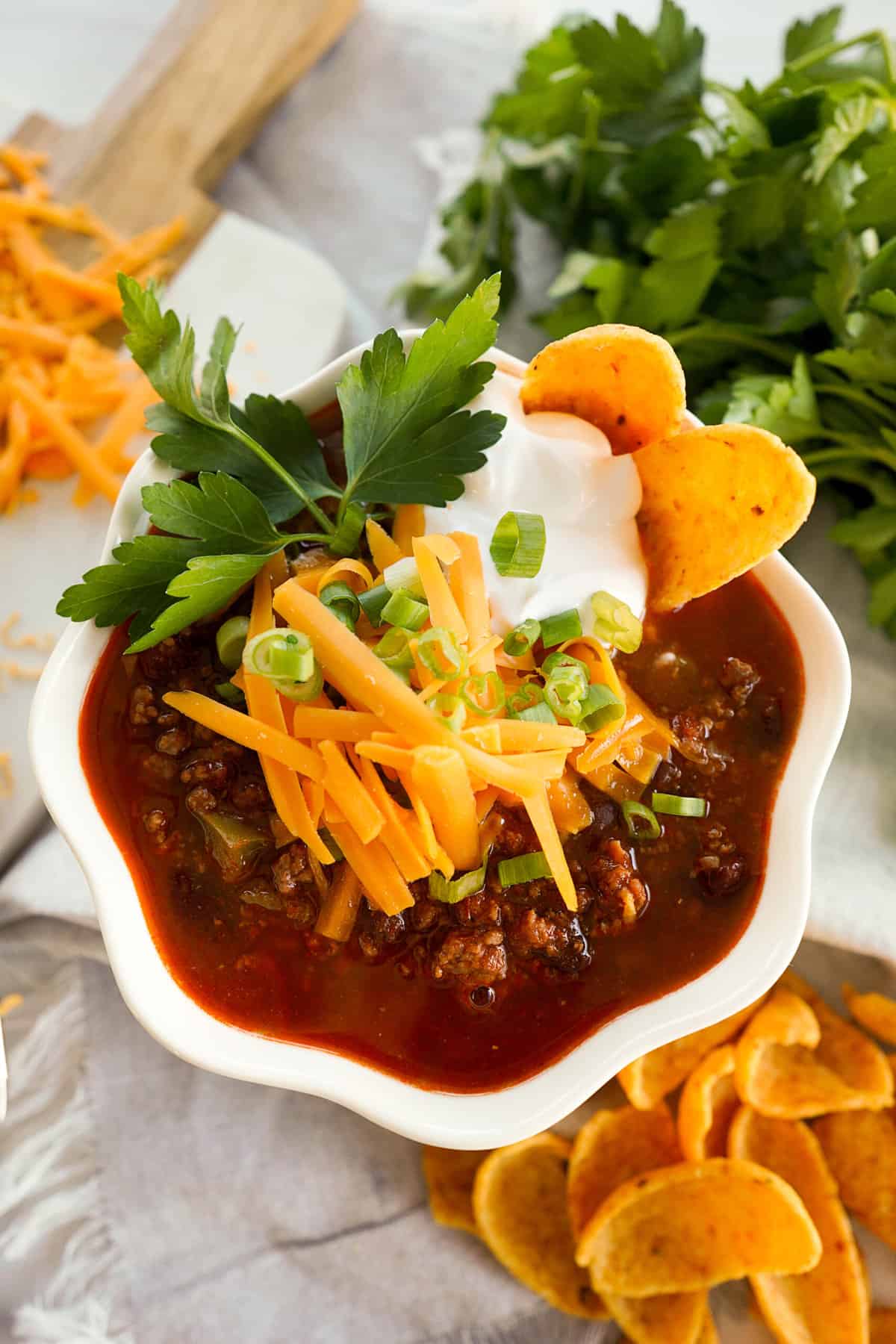 bowl of chili with sour cream, cheese, green onions and corn chips