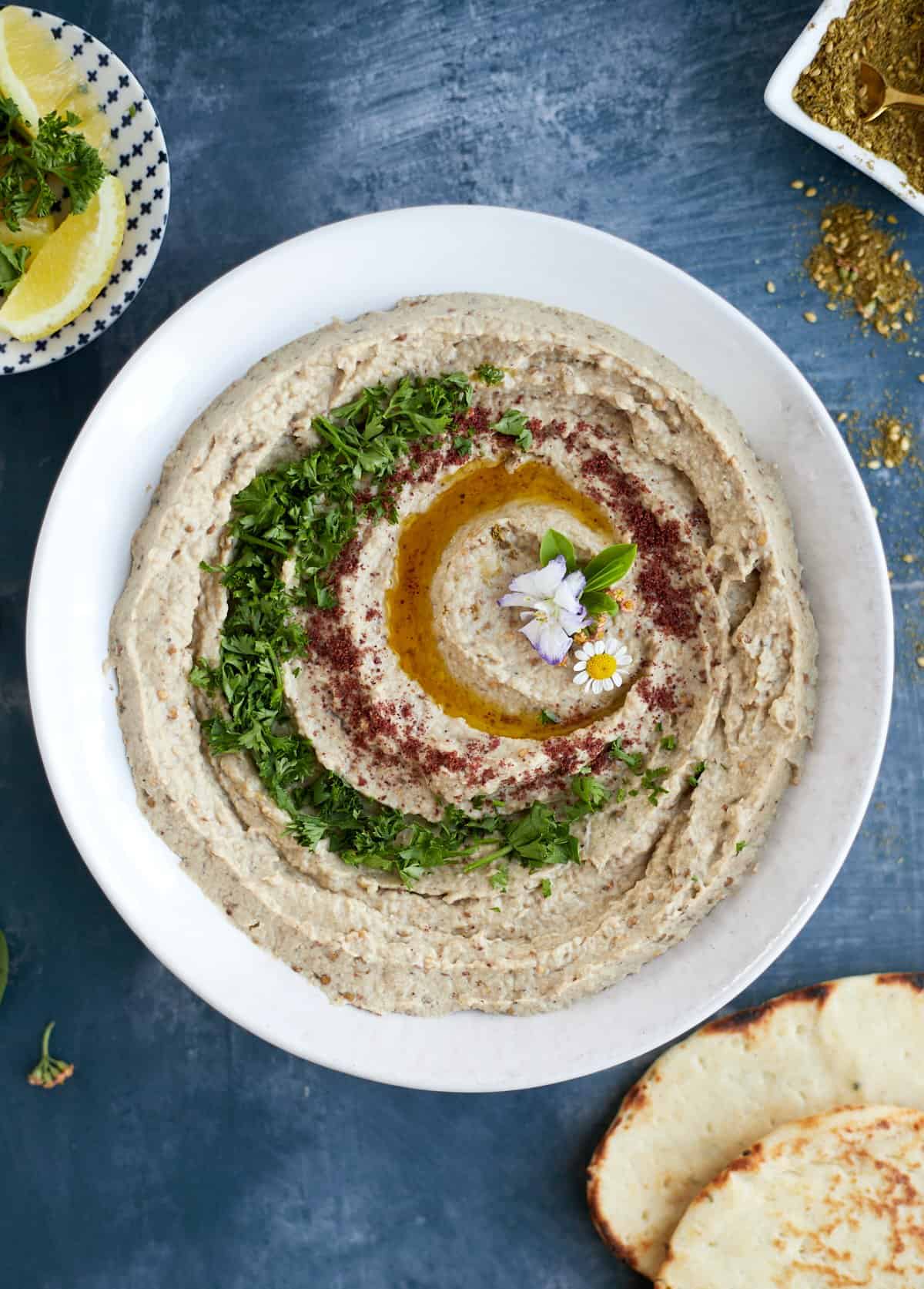 overhead of baba ganoush on a plate with olive oil and fresh parsley