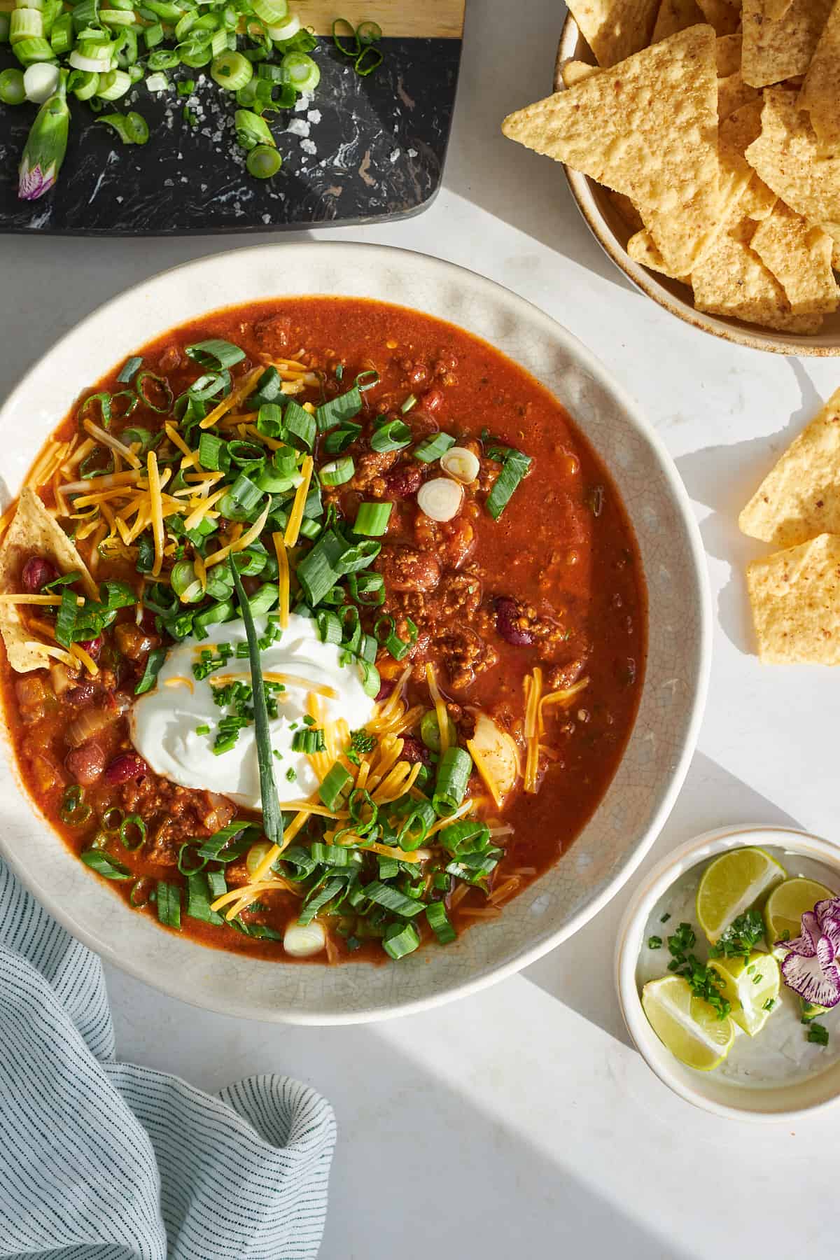 A bowl of slow cooker chili topped with sour cream, green onion, and cheese. 