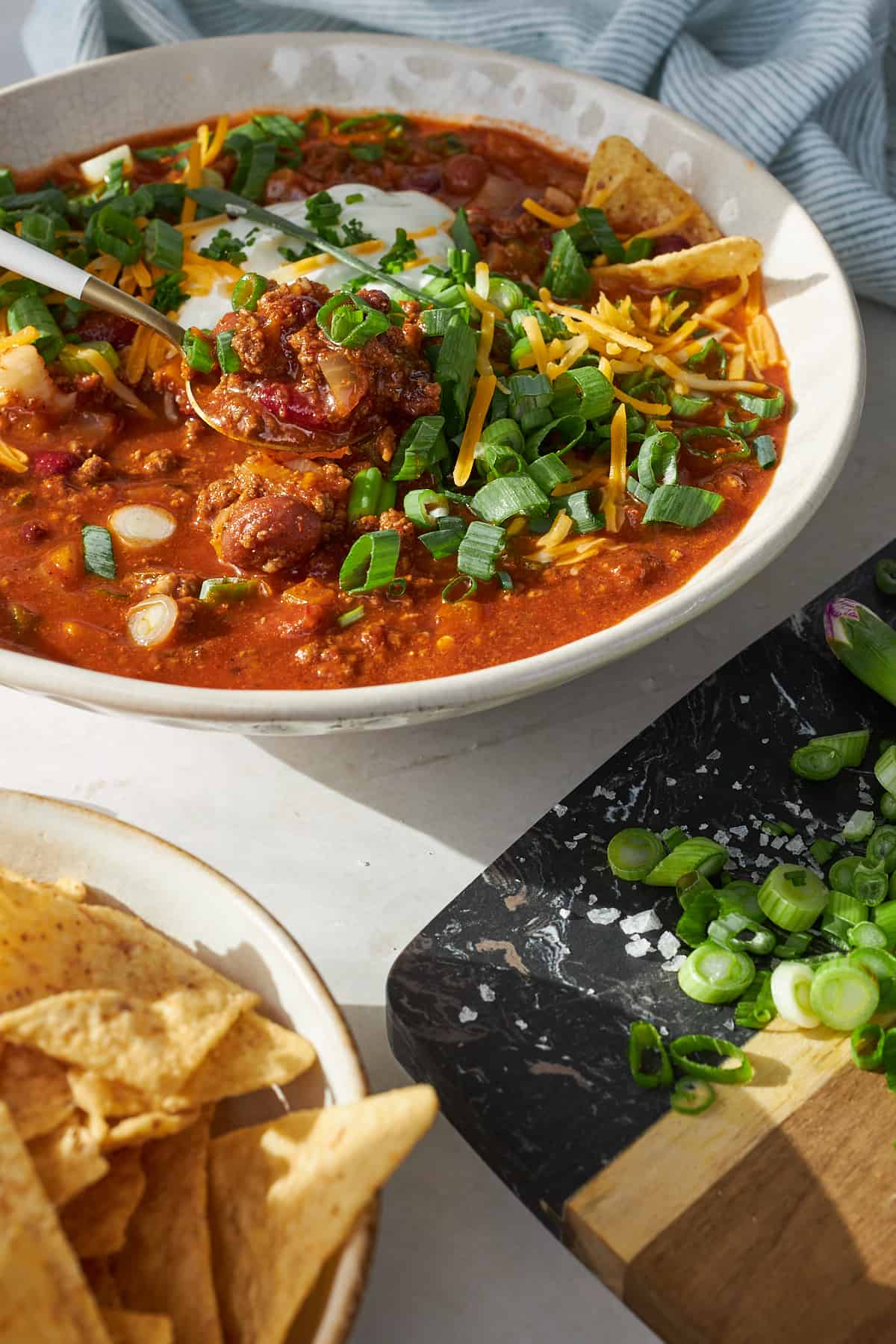 A spoon lifting a bite of slow cooker chili from a bowl. 