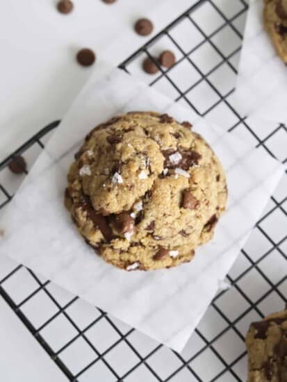 a large browned butter chocolate chip cookie on a piece of parchment paper on a wire rack