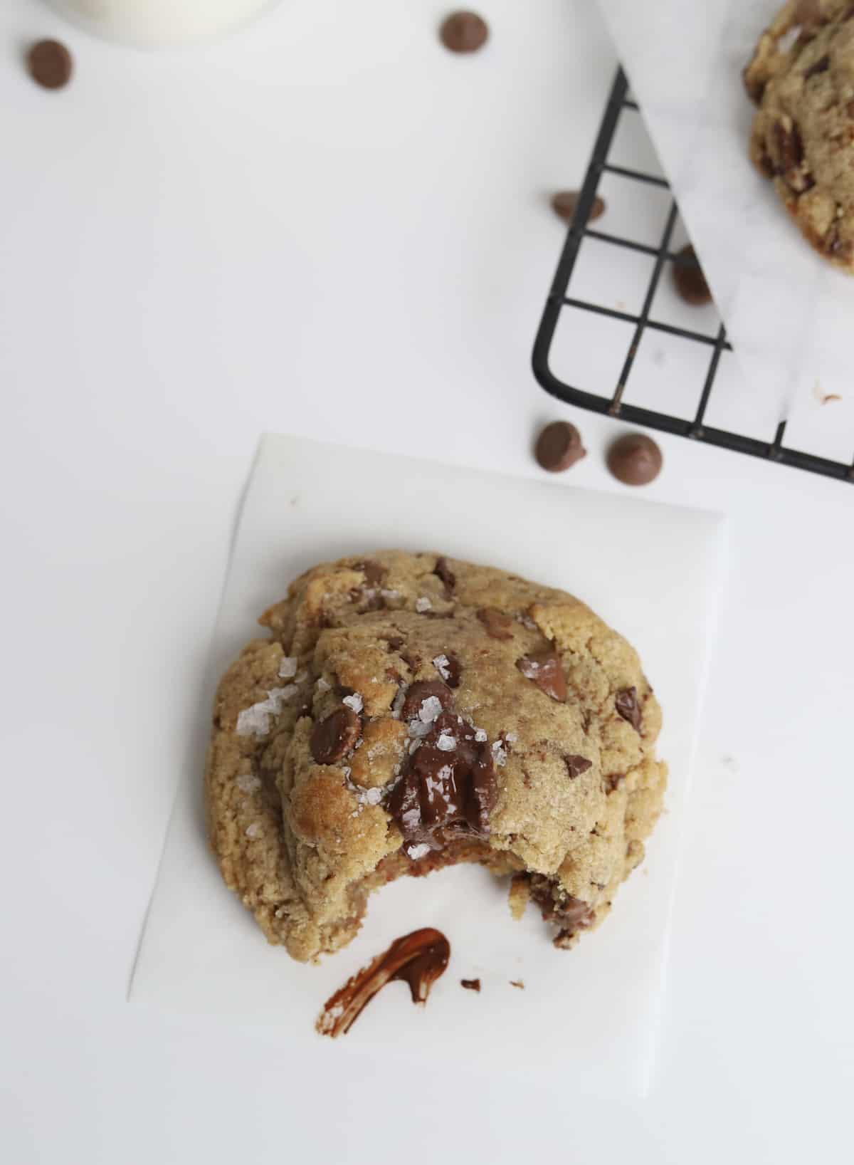 overhead of one bitten browned butter chocolate chip cookie on a wire rack