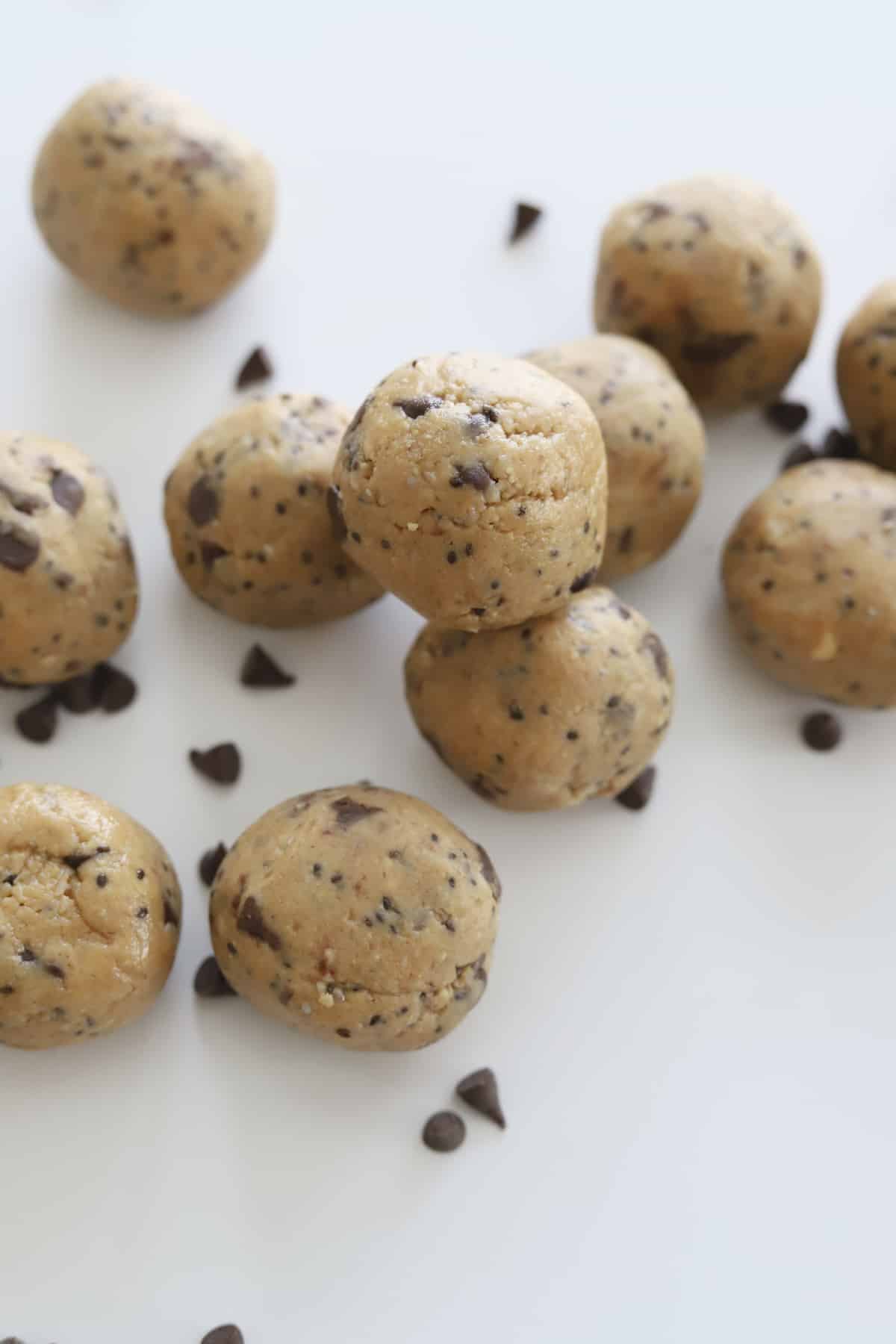 a pile of peanut butter energy balls with chocolate chips surrounding them 