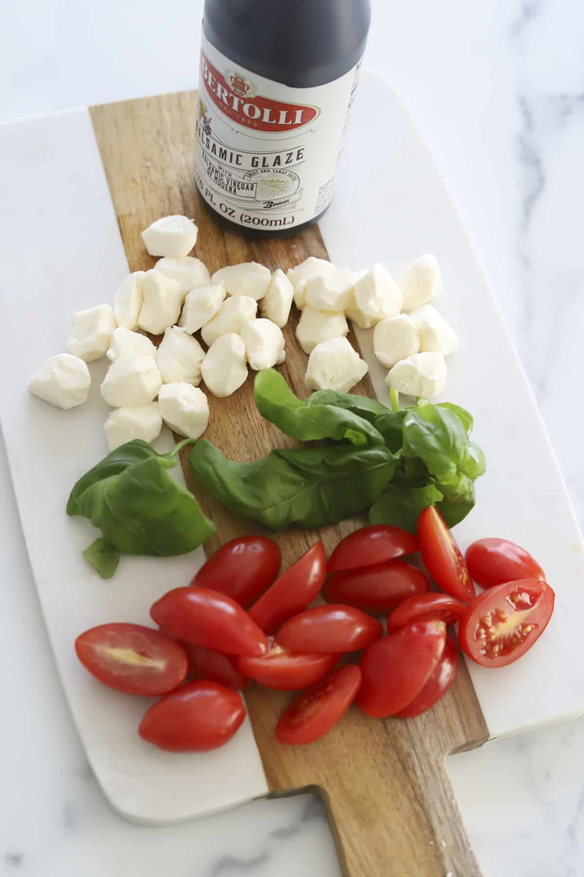 overhead ingredients for avocado caperse toast with balsamic glaze, fresh basil, mozzarella cheese and tomatoes.