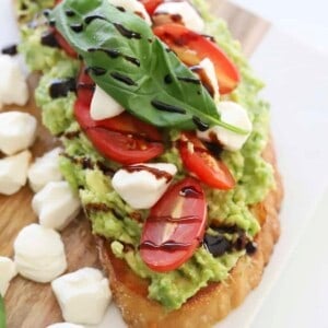 overhead of avocado caperse toast with balsamic glaze and fresh basil