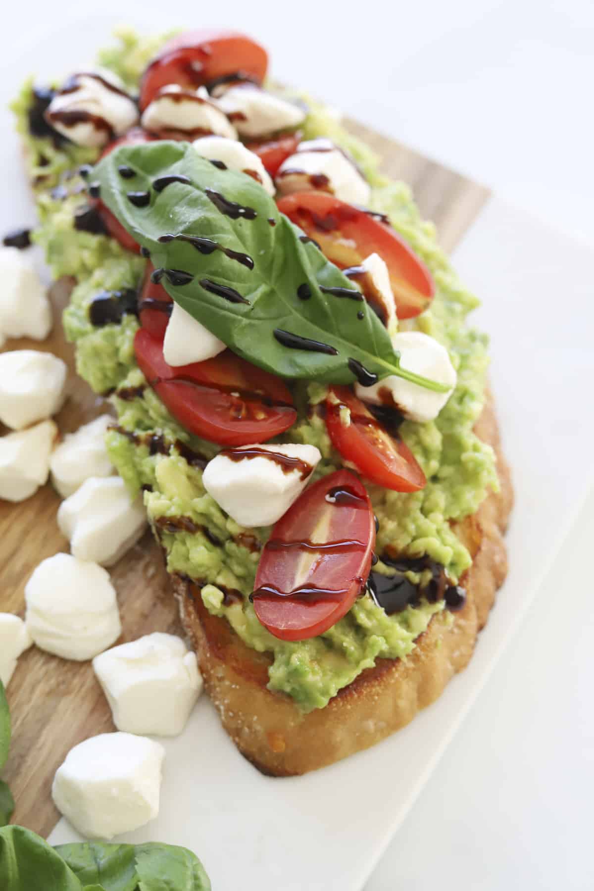 overhead of avocado caperse toast with balsamic glaze and fresh basil