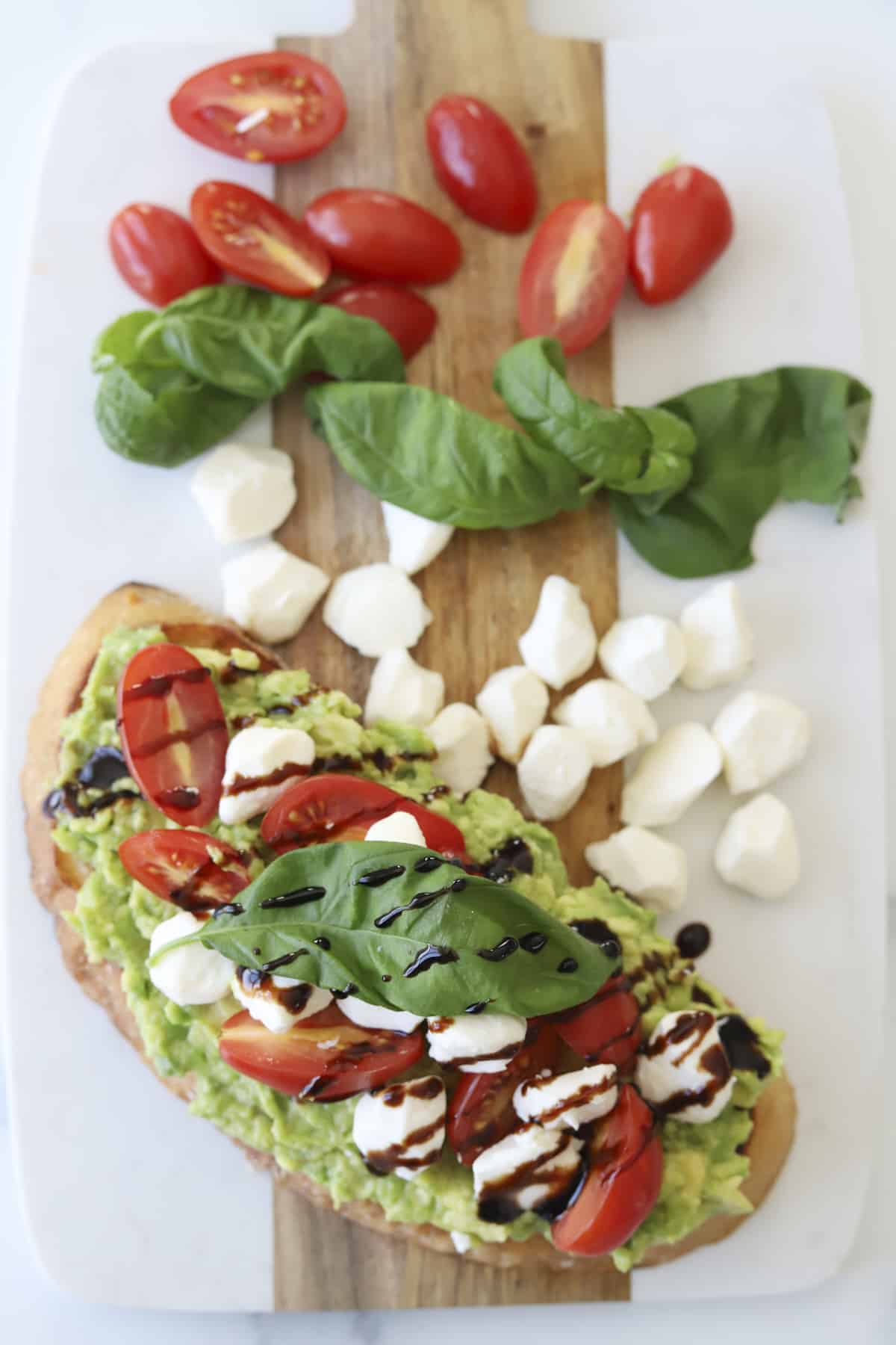 overhead of avocado caperse toast with balsamic glaze and fresh basil