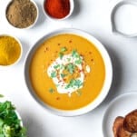 a bowl of Egyptian lentil soup with spices around it