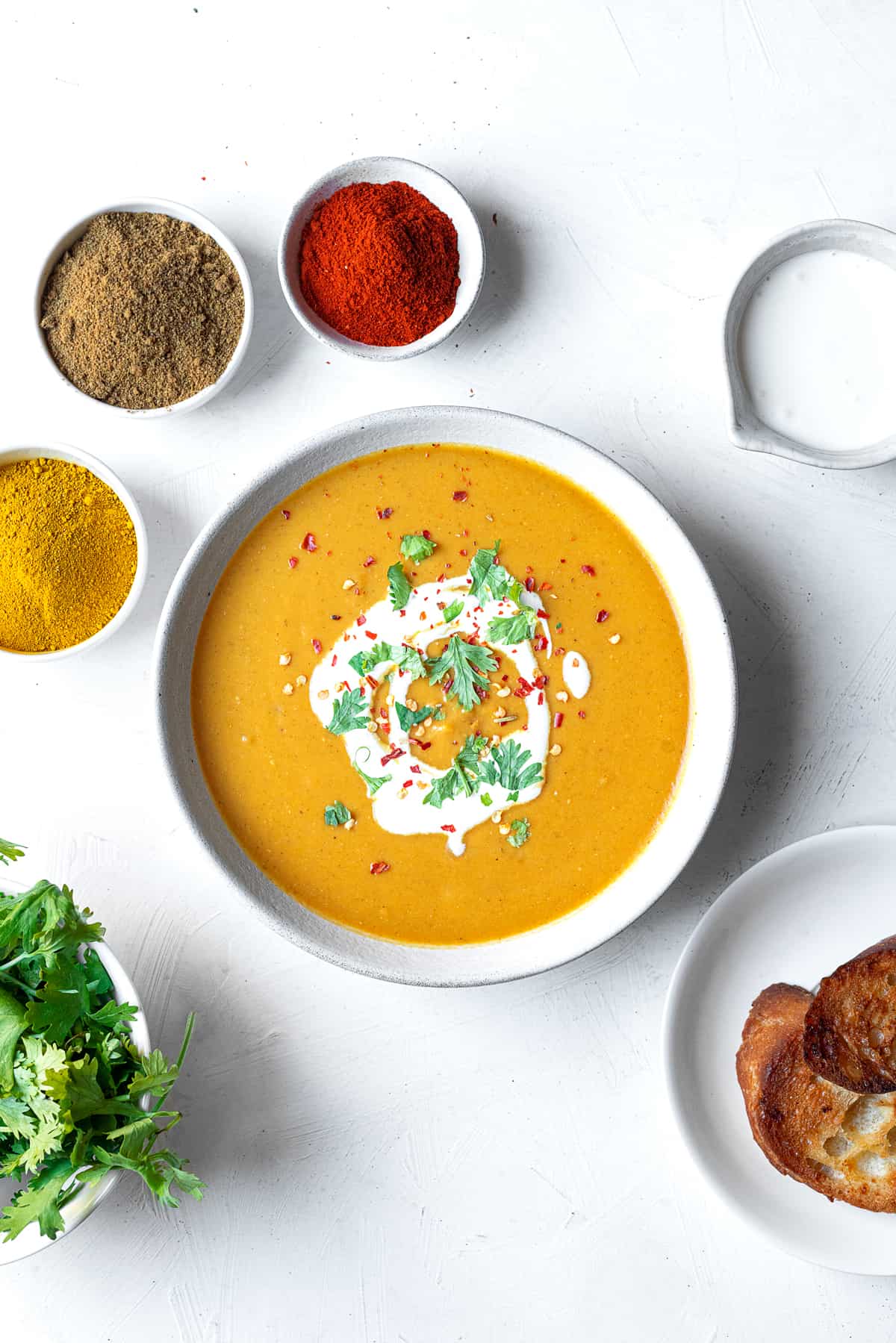 a bowl of Egyptian lentil soup with spices around it