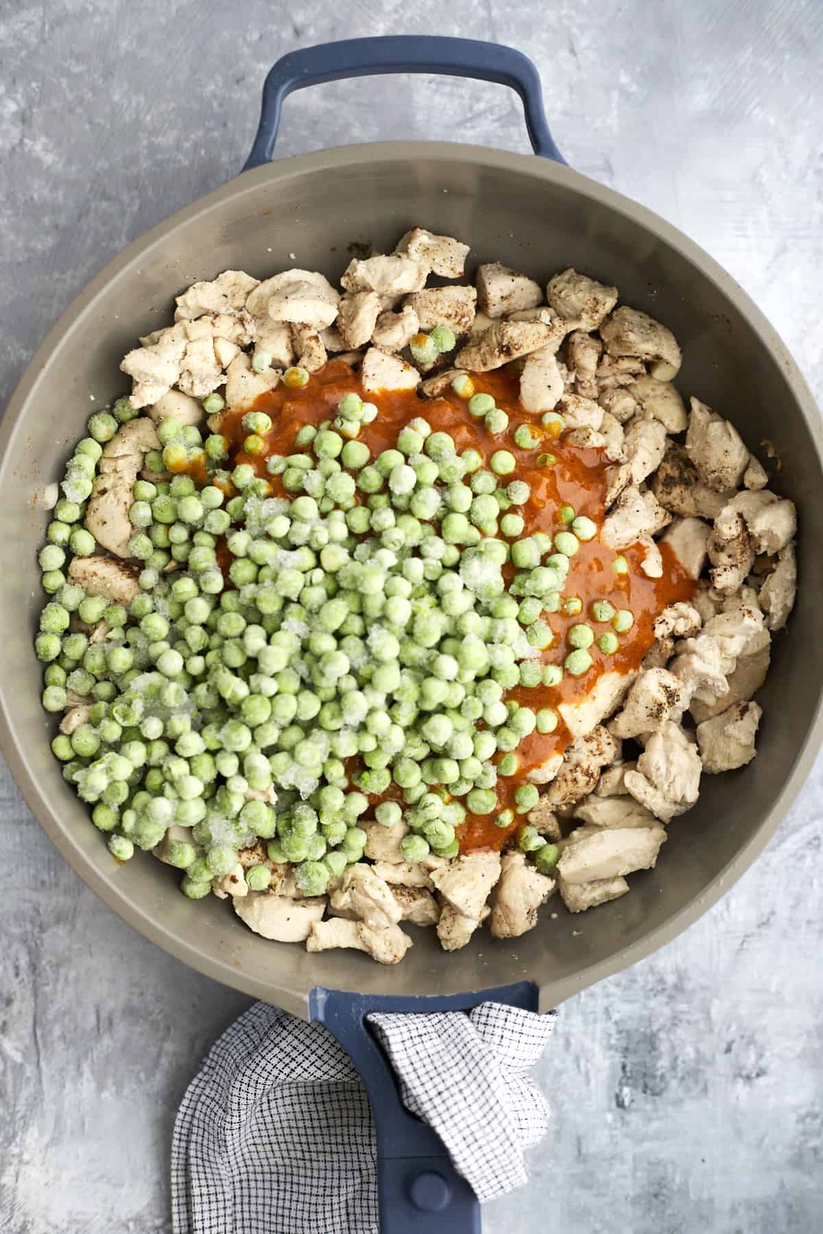 chicken pieces, curry sauce, and frozen peas in a skillet
