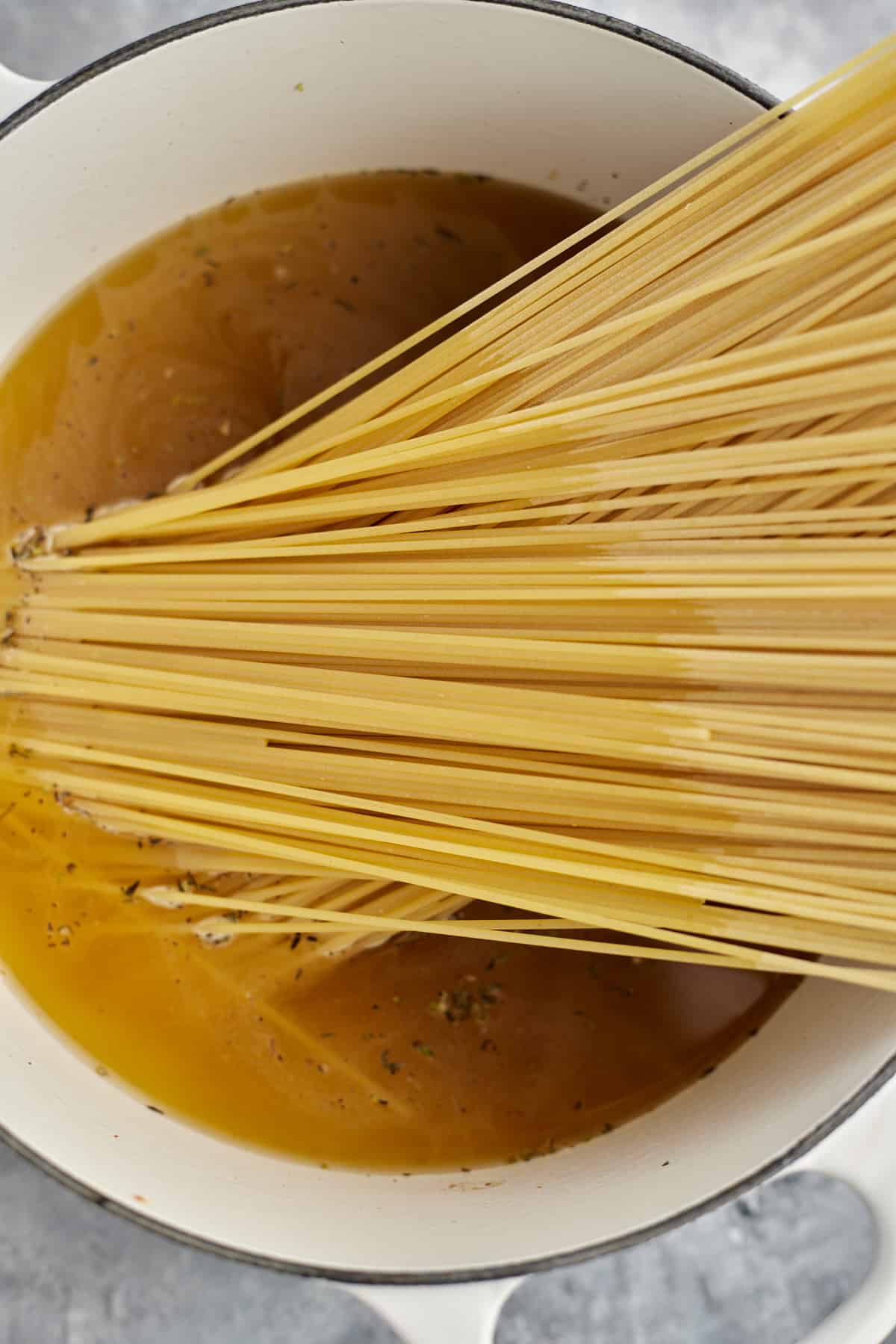 spaghetti noodles in a pot with broth to make spaghetti carbonoara